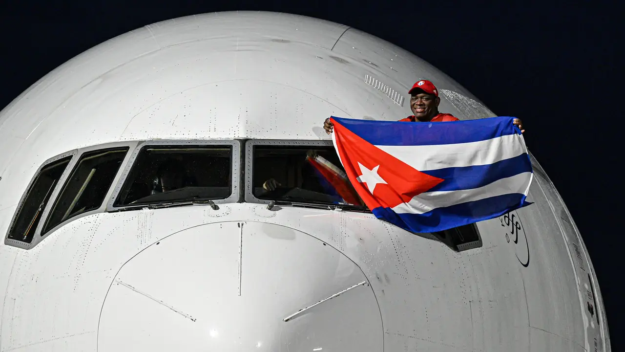 El luchador cubano Mija&iacute;n L&oacute;pez, cinco veces campe&oacute;n ol&iacute;mpico, sostiene una bandera de Cuba en la ventanilla del piloto a su llegada este lunes al aeropuerto Jos&eacute; Mart&iacute; de La Habana. EFE/ AFP /Adalberto Roque/POOL